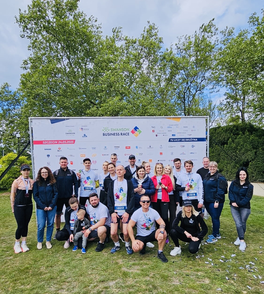 Galan Logistics at Swanson Business Race 2025 – seven teams, shared energy, and team integration in front of the sponsor wall.